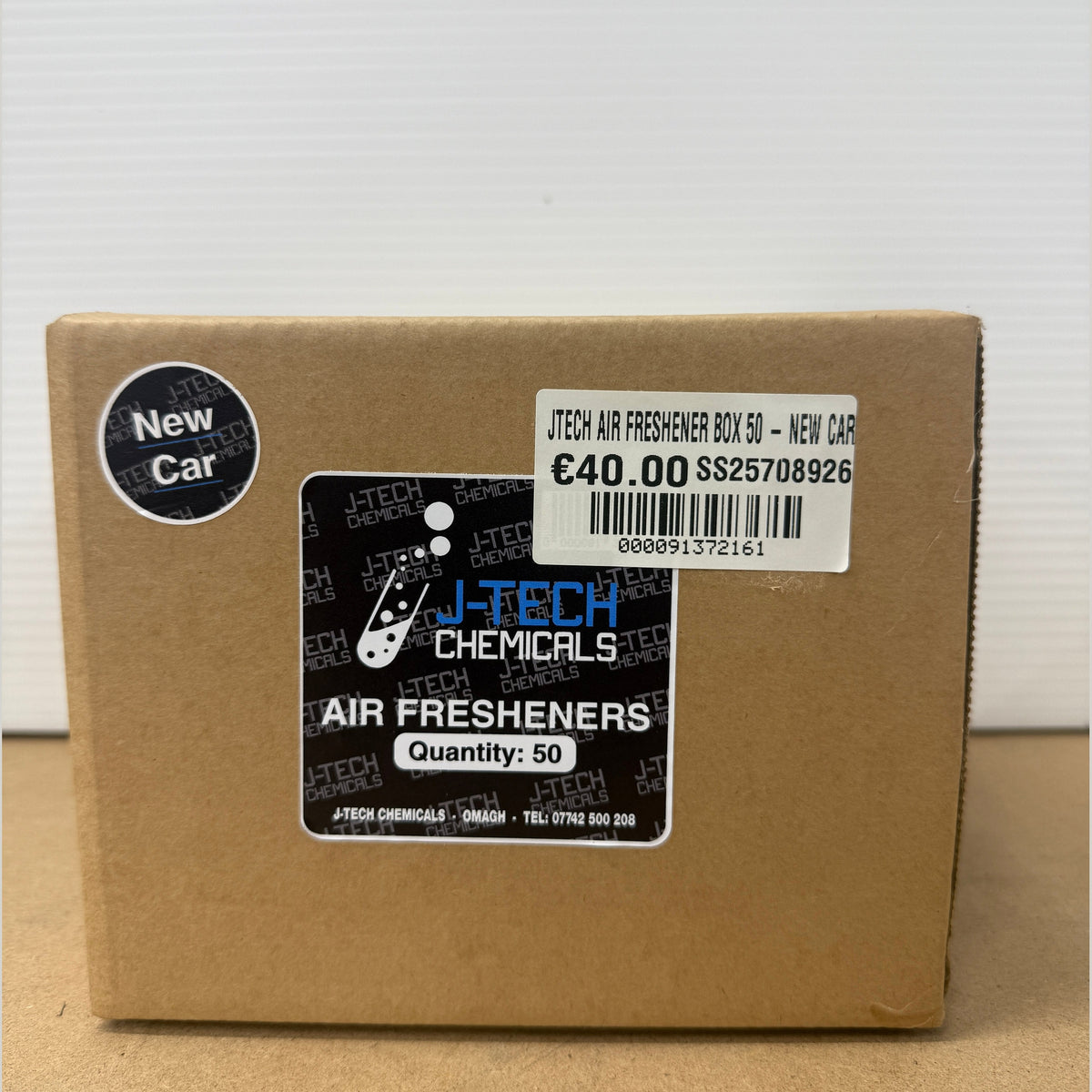 Cardboard box with J-Tech Chemicals air freshener packaging on a white background